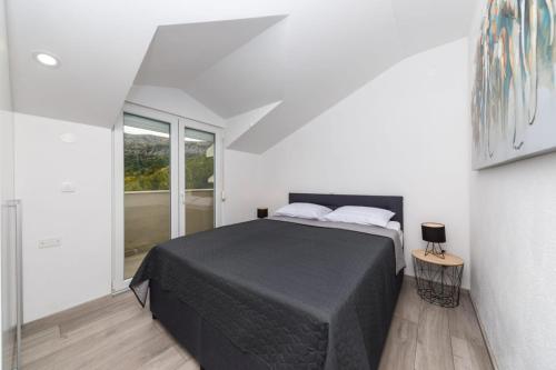 una camera da letto con un letto nero in una stanza bianca di Sun Apartment Klis a Klis