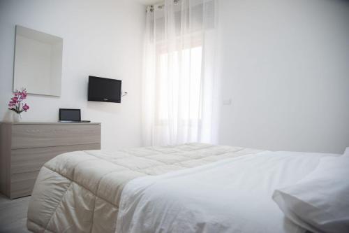 ein weißes Schlafzimmer mit einem weißen Bett und einem Fenster in der Unterkunft Casa al Corso in Benevento