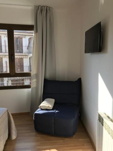 a blue couch sitting in a room with a window at Hostal Casiano Camarasa in Camarasa