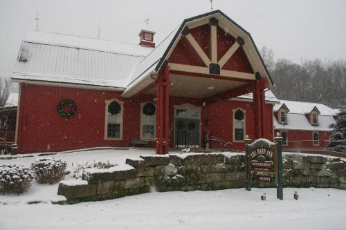 a red building in the snow with a sign in front at The Barn Inn Bed and Breakfast in Millersburg