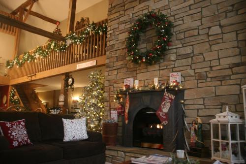 a living room with a stone fireplace with christmas decorations at The Barn Inn Bed and Breakfast in Millersburg