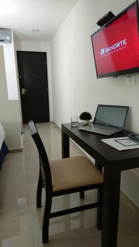 a desk with a laptop and a chair in a room at Hotel MB in Campeche