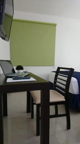 a desk with a laptop and a chair in a room at Hotel MB in Campeche