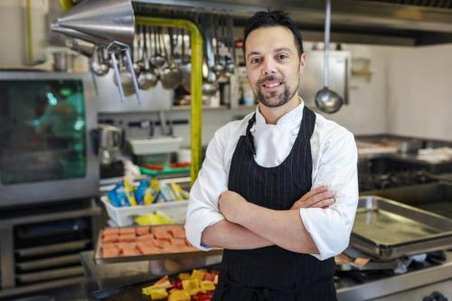 a man standing in a kitchen with his arms crossed at Aqua Hotel in Rimini