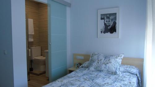 - une chambre avec un lit et une photo sur le mur dans l'établissement PENSION OVIEDO, à Oviedo