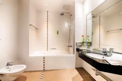 a bathroom with two sinks and a shower and a tub at Welcome Hotel Residenzschloss Bamberg in Bamberg