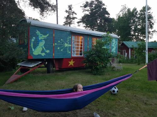 una donna sdraiata su un'amaca in un cortile con una casa di Cirkus Hostel Holken a Inkoo