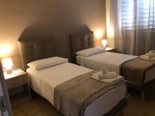 two beds in a hotel room with towels on them at B&B Altamarea in Falerna