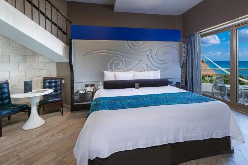 a bedroom with a large bed with a blue accent wall at Hard Rock Hotel Riviera Maya - Heaven Adults Only - All Inclusive in Puerto Aventuras
