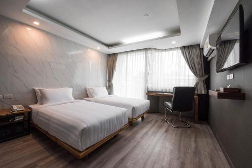a hotel room with two beds and a desk at Bangkok City Link Hotel in Bangkok