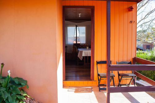 una casa de color naranja con una mesa y sillas en el porche en Pousada Barth en Canela