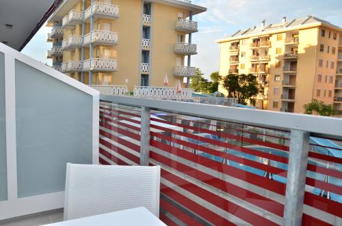 a balcony with two white chairs and some buildings at Hotel Amburgo in Bibione