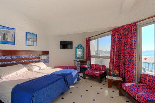 a bedroom with a bed and two chairs and a window at UMH Tarik Hotel in Tangier