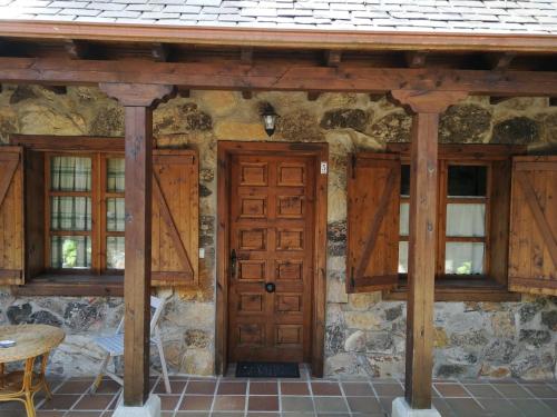 uma casa de pedra com portas e janelas de madeira em Alojamientos Rurales El Fontano em Galende