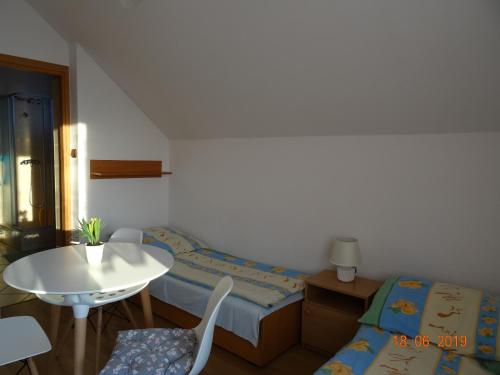スバジェボにあるPokoje gościnne Olkaのベッド2台、テーブル、椅子が備わる小さな客室です。