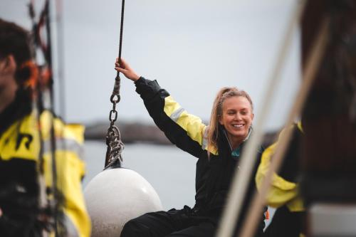 a woman is sitting on a rope swing at Solsiden Brygge Rorbuer in Ballstad