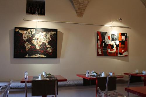 a dining room with tables and paintings on the walls at Hotel Sorella Luna in Assisi