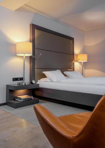 a bedroom with a bed with two lamps and a chair at Zum Löwen Design Hotel Resort & Spa in Duderstadt
