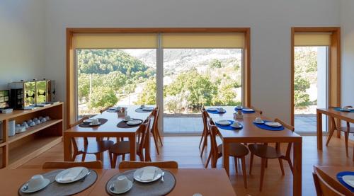a dining room with tables and chairs and a large window at Alojamento Santa Clara in Manteigas