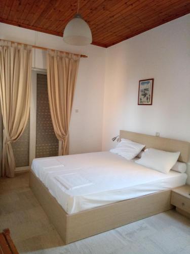 a bedroom with a large white bed with curtains at Villa Fotis in Ligia