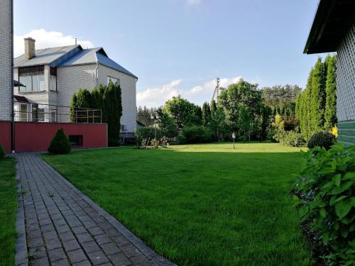 a yard with a house and a grassy field at Arvydo Gylio sodyba in Ignalina