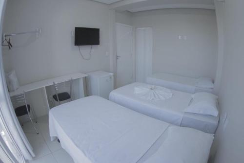 a white room with two beds and a tv at Grande Hotel in Gurupi