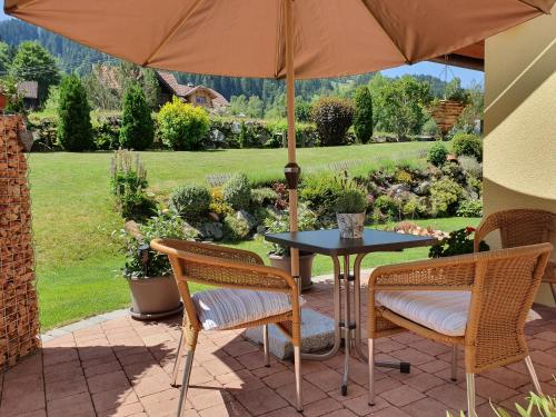 un patio con mesa, sillas y sombrilla en Appartement BERGTRÄUME, en Haus im Ennstal