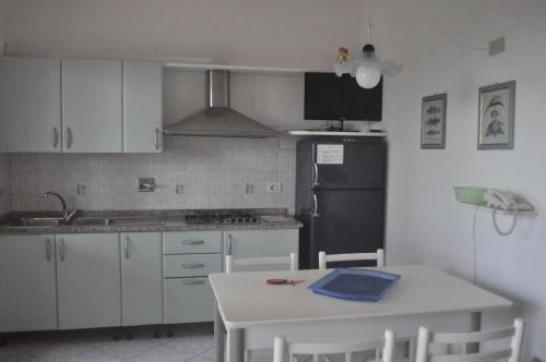 a kitchen with a white table and a black refrigerator at Residence Belvedere in Capoliveri