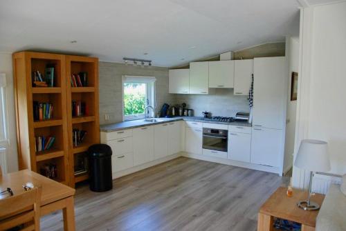cocina con armarios blancos y suelo de madera en Villa Pantano, en Berkhout