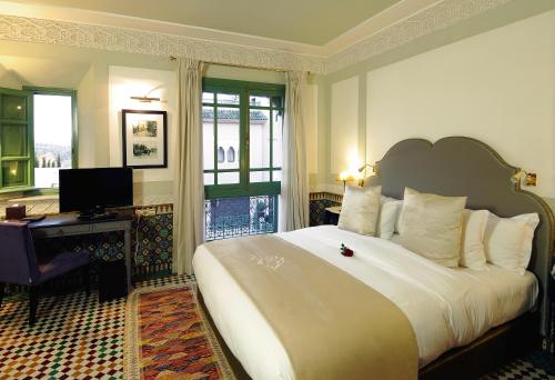 a hotel room with a large bed and a desk at Palais Faraj Suites & Spa in Fès