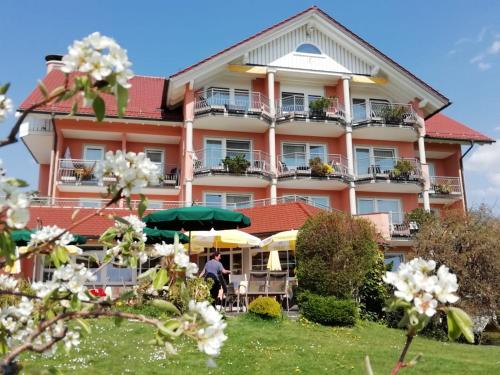 a large pink building with tables and umbrellas at Hotel-Restaurant Walserhof in Wasserburg am Bodensee