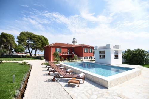 une piscine avec des chaises longues et une maison dans l'établissement Puntamika Laterna, à Zadar