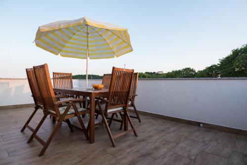 una mesa y sillas con una sombrilla en el balcón en Apartments MARIO, en Malinska