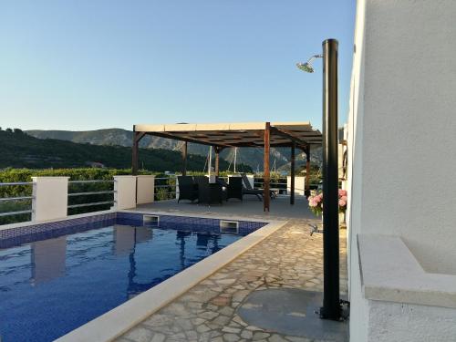 een huis met een zwembad en een paviljoen bij Fei Fei Apartments in Račišće