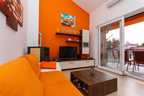 an orange living room with a couch and a tv at Seafront Apartment Soline With Seaview in Soline