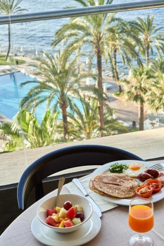 a table with two plates of food and a view of the ocean at Palace Bonanza Playa Resort & SPA by Olivia Hotels Collection in Illetas