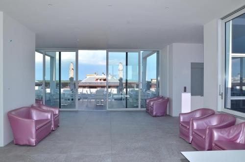 a waiting room with pink chairs and windows at Hotel Amburgo in Bibione