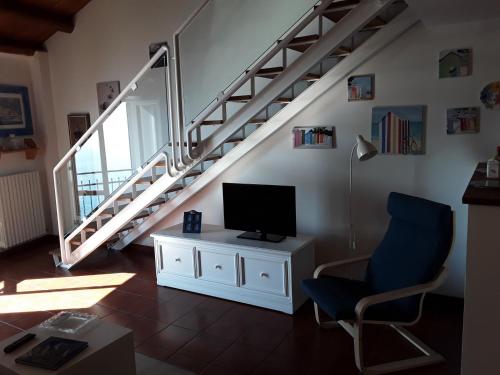 a living room with a chair and a tv and stairs at loft sul mare Sirolo in Sirolo
