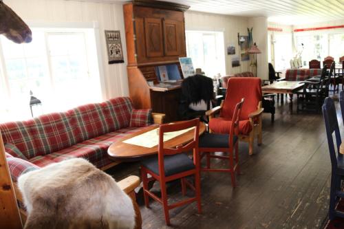 a living room with a couch and tables and chairs at Gamlestølen Fjellstue in Etnedal