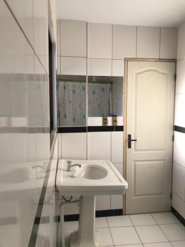 een witte badkamer met een wastafel en een deur bij Cittadella Hostal in Sucre