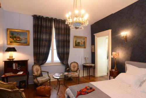 a bedroom with a bed and chairs and a chandelier at Benigne Malyon in Dijon