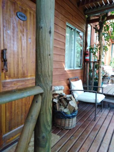 a porch of a wooden cabin with a chair and a window at Cabañas Spa Bungalows Huarranchi in Pucón