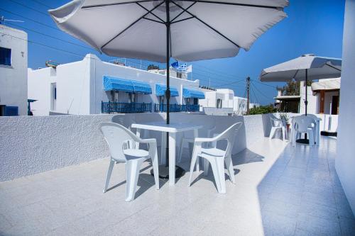 a white table and chairs and an umbrella on a balcony at LALOS Rooms in Parikia