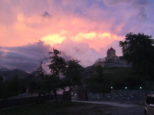 a castle on top of a hill with a cloudy sky at Guesthouse AlpenRose in Mestia