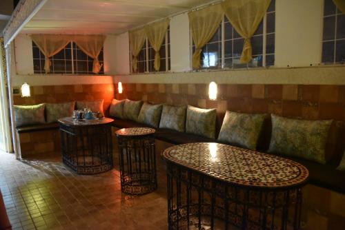 a bar with a couch and tables and windows at Riad Najiba in Rabat