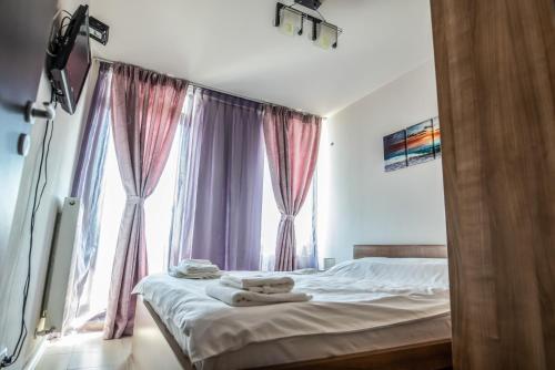 a bedroom with a bed with pink curtains and a window at Neptun Blue Apartament in Neptun