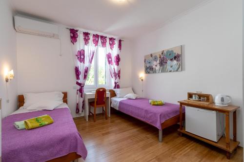 a bedroom with two beds with purple sheets and a table at Marica Guesthouse in Vela Luka