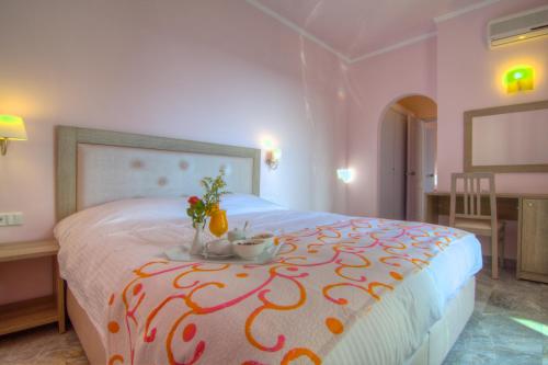 a bedroom with a bed with a table with flowers on it at Solimar Dias Hotel in Adelianos Kampos