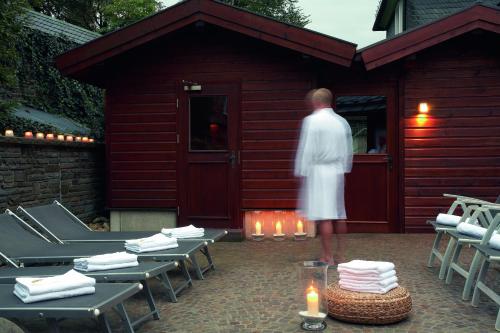 a man in a white robe standing outside of a cabin at Romantik Berghotel Astenkrone in Winterberg