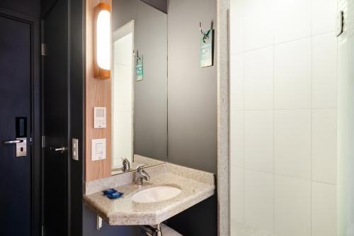 uma casa de banho com um lavatório e um espelho em ibis budget Sao Caetano em São Caetano do Sul